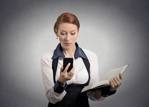 woman reading news on smart phone holding book