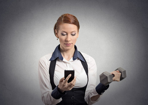 woman reading news on smartphone lifting dumbbell