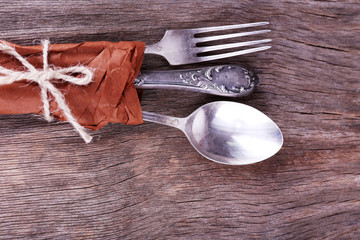 Tableware wrapped in paper on wooden background