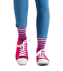 Female legs in colorful socks and sneakers isolated on white