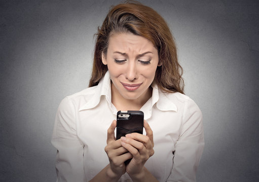 Sad woman looking at mobile phone bad news very upset