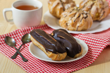 Tasty eclairs on table with tea cup