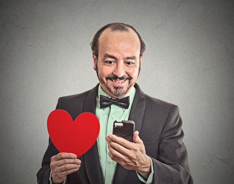 happy man checking his smart phone, holding red heart