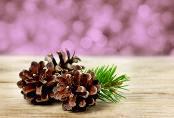 pine cones on a wooden board against christmas bokeh background