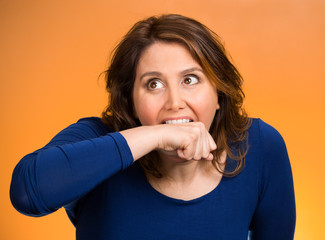crazy woman going nuts biting her arm orange background 
