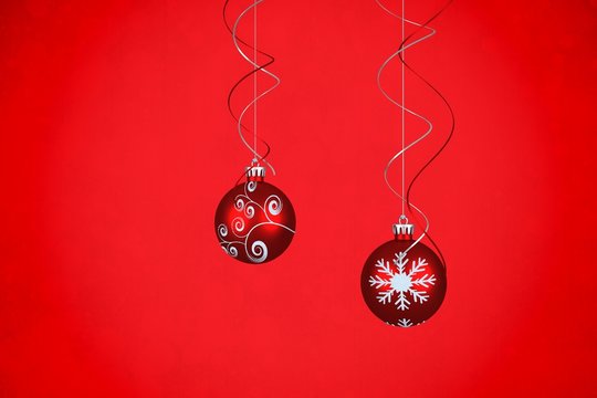 Composite image of two hanging red bauble decorations