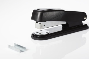 Black stapler and staples against white background
