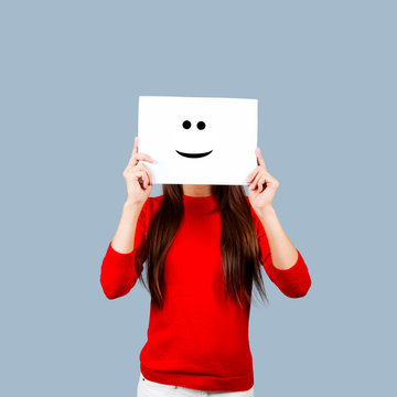 Girl holding a paper with a happy face painted Isolated on White