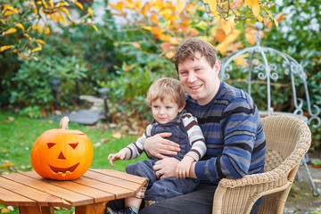 Young man and toddler boy making halloween pumpkin