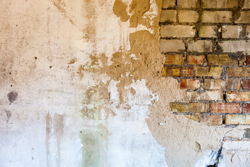 Old brick wall with the damaged plaster