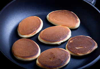 six pancakes in a frying pan