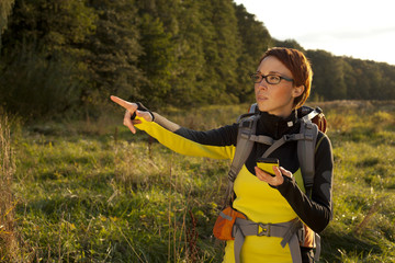 Young woman with backpack in a meadow showing way . Hiking at su - 71601627