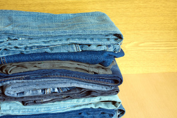 Colored jeans on cupboard shelf, front view close-up