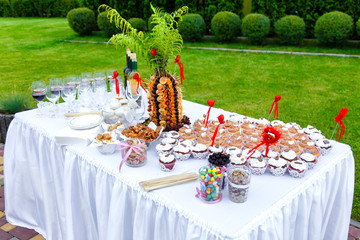 Muffins with hearts, sweets, fruits and vine on the banquet tabl