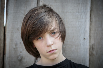 closeup portrait of a teenage boy in front of a wood background
