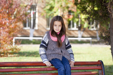 Beautiful little girl sitting on a bench