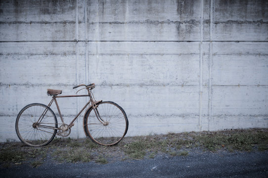 Antique or retro oxidized bicycle outside on a concrete wall