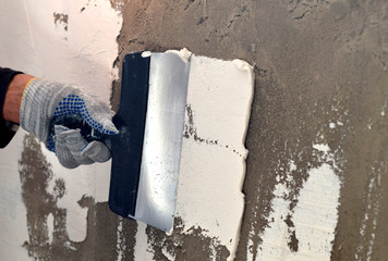 The process of applying a white putty on concrete gray wall