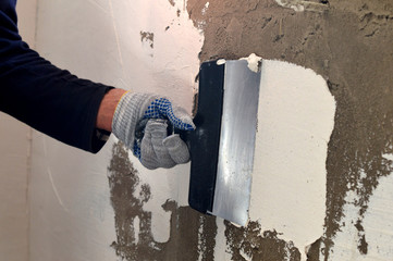 The process of applying a white putty on concrete gray wall