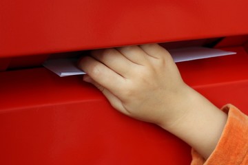 children's hand putting letters mailbox