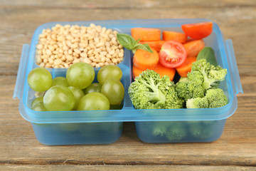 Tasty vegetarian food in plastic box on wooden table