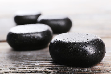 Spa stones with drops on wooden background