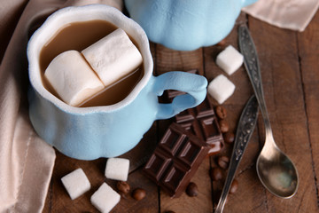 Cup of coffee with marshmallow and chocolate on wooden table