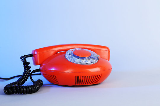 Old red disk phone on blue background