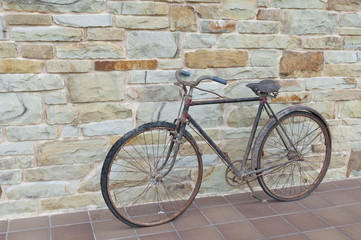 Naklejka na ściany i meble Antique or retro oxidized bicycle outside on a stone wall