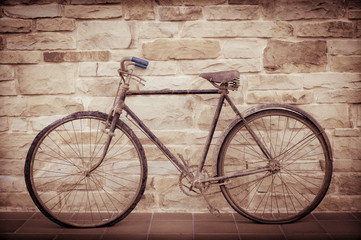Fototapeta na wymiar Antique or retro oxidized bicycle outside on a stone wall