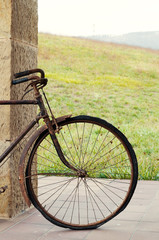Fototapeta premium Antique or retro oxidized bicycle outside on a stone wall