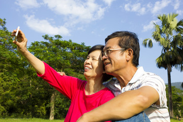 Senior couple sitting on grassland and  taking picture