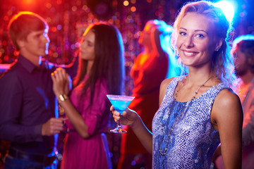 Beautiful girl posing with cocktail in nightclub
