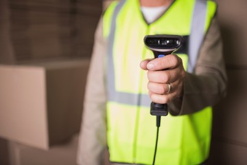 Mid section of worker with scanner in warehouse