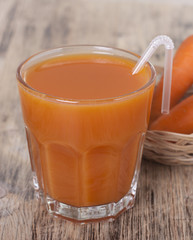Carrot juice in a glass and carrots on the table.