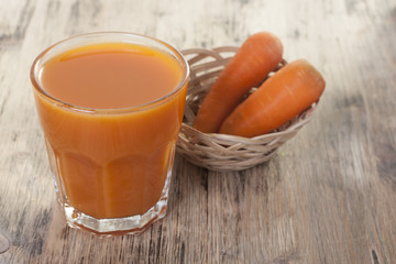 Carrot juice in a glass and carrots on the table.