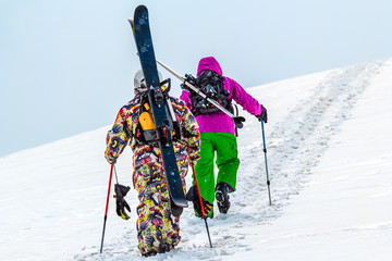 Two skiers rise walk uphill