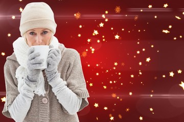 Composite image of woman in warm clothing holding mugs