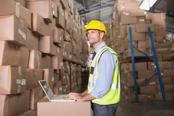 Workman with laptop at warehouse