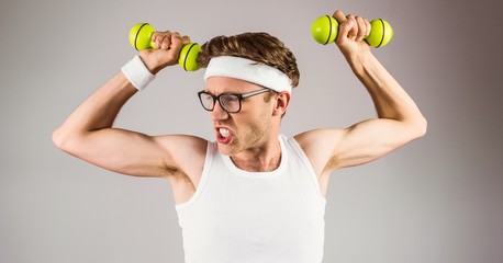 Geeky hipster posing in sportswear with dumbbells