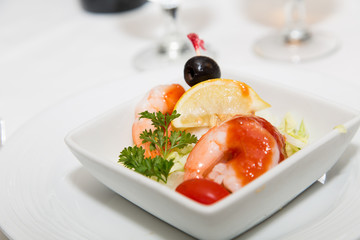 Shrimp Cocktail Garnished with Lemon Wedge and Black Olive
