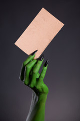 Green monster hand holding blank piece of cardboard