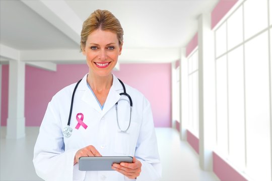 Composite image of blonde doctor using tablet pc