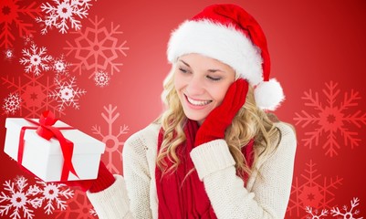 Composite image of happy festive blonde with gift