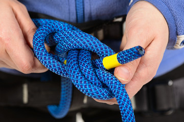 Female hands holding a climbing rope making a secure node