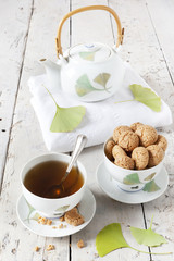 tea on cup with teapot and amaretti sweets on white table