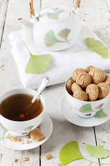 tea on cup with teapot and amaretti sweets on white table