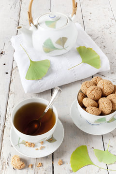tea on cup with teapot and amaretti sweets on white table