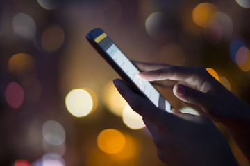 Woman using her mobile phone , night light background