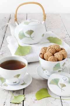 tea on cup with teapot and amaretti sweets on white table